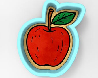 Peut inclure: Emporte-pièce en forme de pomme rouge avec une tige marron et une feuille verte. La pomme est soulignée en noir et placée dans un cadre bleu clair. Conçu pour la pâtisserie et le bricolage.