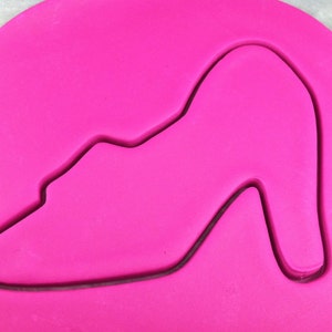 May include: A pink fondant cutout of a high-heeled shoe.