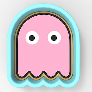 Könnte beinhalten: Hellblauer Ausstecher in Form eines rosa Geistes mit schwarzen Augen. Der Geist hat einen gelben und schwarzen Rand. Der Ausstecher hat einen wellenförmigen unteren Rand, ideal für Backwaren.