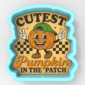 Puede incluir: Cortador de galletas azul claro con un diseño de calabaza de dibujos animados. La calabaza lleva una gorra verde y hace el signo de la paz. El texto dice "Cutest Pumpkin in the Patch" en naranja y marrón.