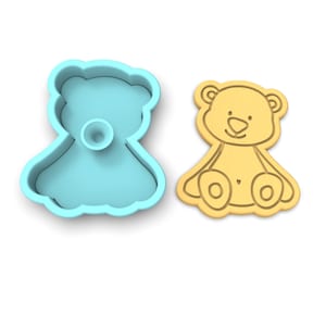 K&ouml;nnte beinhalten: Ein blauer Plastik-Ausstecher und ein hellbrauner Keks in Form eines Teddyb&auml;ren.