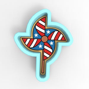 May include: A pinwheel cookie cutter in the shape of a pinwheel with red and white stripes, blue sections with white stars, and a brown center. The pinwheel is outlined in gold and set within a light blue frame.