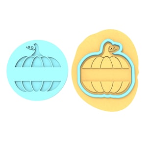 Op de afbeelding: Een blauwe plastic koekjesvormer in de vorm van een pompoen met een lege ruimte voor personalisatie. De vormer wordt getoond op een geel oppervlak.