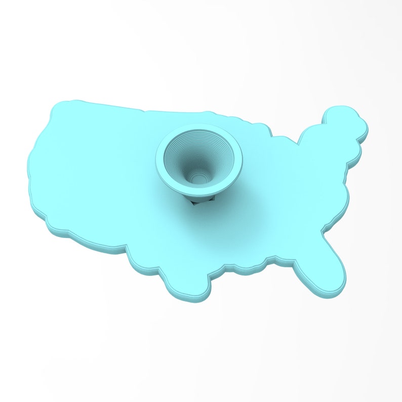 Pu&ograve; includere: Un supporto per telefono in silicone blu chiaro a forma di contorno degli Stati Uniti. Il supporto ha una piccola area circolare incassata al centro.