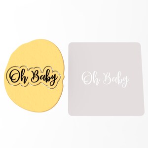 May include: A cookie cutter and stencil set featuring the phrase "Oh Baby" in a cursive font. The cookie cutter is black and the stencil is white.