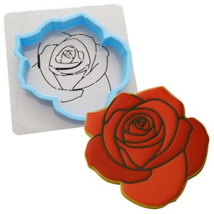a cookie cutter next to a cookie shaped like a rose