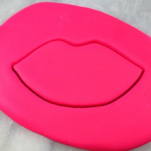May include: Pink fondant with a cutout of a red lip shape.