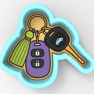 Puede incluir: Cortador de galletas con forma de llave de coche, con un contorno azul claro. El cortador presenta una llave de coche, un llavero con símbolos de bloqueo y desbloqueo, y una borla verde. El llavero es morado y la llave es dorada y negra.