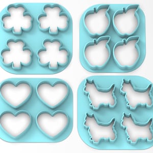 May include: Set of four blue plastic cookie cutters, each with a different design: a four-leaf clover, an apple, a heart, and a terrier dog.