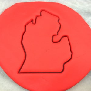 Könnte beinhalten: Ein Blatt roter Keksteig mit einem Ausstecher in Form des Bundesstaates Michigan.