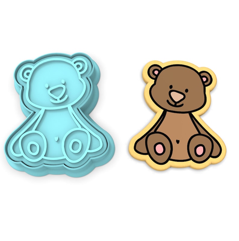 K&ouml;nnte beinhalten: Ein blauer Plastik-Ausstecher in Form eines Teddyb&auml;ren, neben einem braunen Zuckerkeks in Form eines Teddyb&auml;ren.