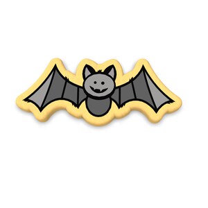 May include: A yellow cookie shaped like a bat with a black and gray bat design. The bat has a smiling face.