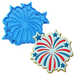 Op de afbeelding: Een blauwe plastic koekjesvormer in de vorm van een vuurwerk met sterren eromheen. Een gedecoreerde koek met rode en blauwe glazuur in de vorm van een vuurwerk.