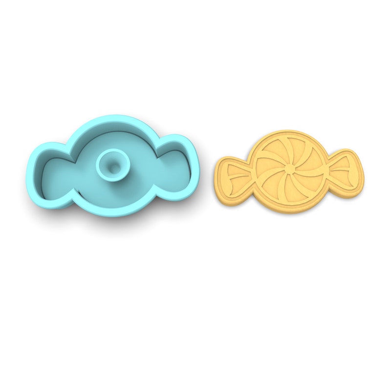 Puede incluir: Un cortador de galletas de pl&aacute;stico azul claro con forma de caramelo con un dise&ntilde;o de espiral. Junto a &eacute;l hay una galleta amarilla cortada en la misma forma.