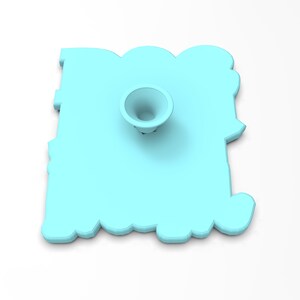 May include: A light blue plastic cookie cutter shaped like the word "Boo" with a small, round, white plastic stand in the center.