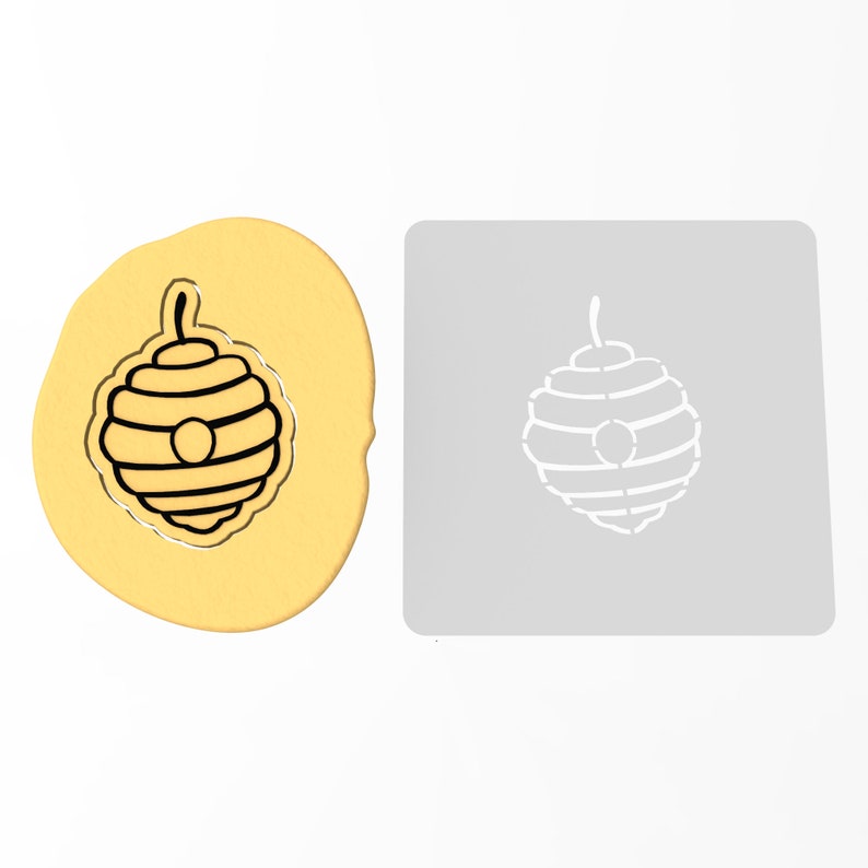 May include: A cookie cutter and a piece of cookie dough, both shaped like a beehive with a round opening at the top.