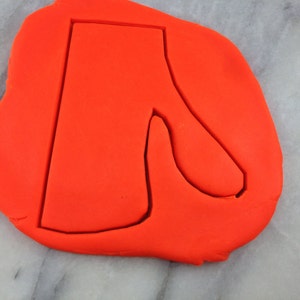 May include: A red cookie cutter in the shape of a boot with a pointed toe.