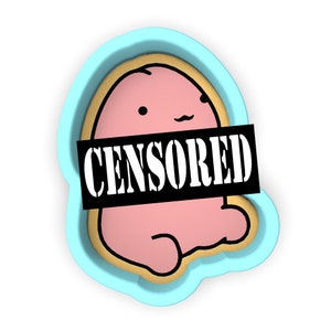 May include: A pink cookie cutter in the shape of a cartoon character with a winking eye and a censored mouth. The cookie cutter is made of blue plastic.