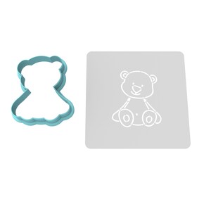 K&ouml;nnte beinhalten: Ein hellblauer Plastik-Ausstecher in Form eines Teddyb&auml;ren und eine graue Schablone mit einem wei&szlig;en Teddyb&auml;r-Motiv.