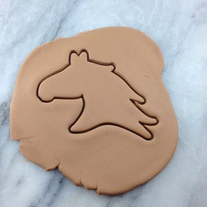 Op de afbeelding: Een bruin koekdeeg met een uitsteekvorm in de vorm van een paard.