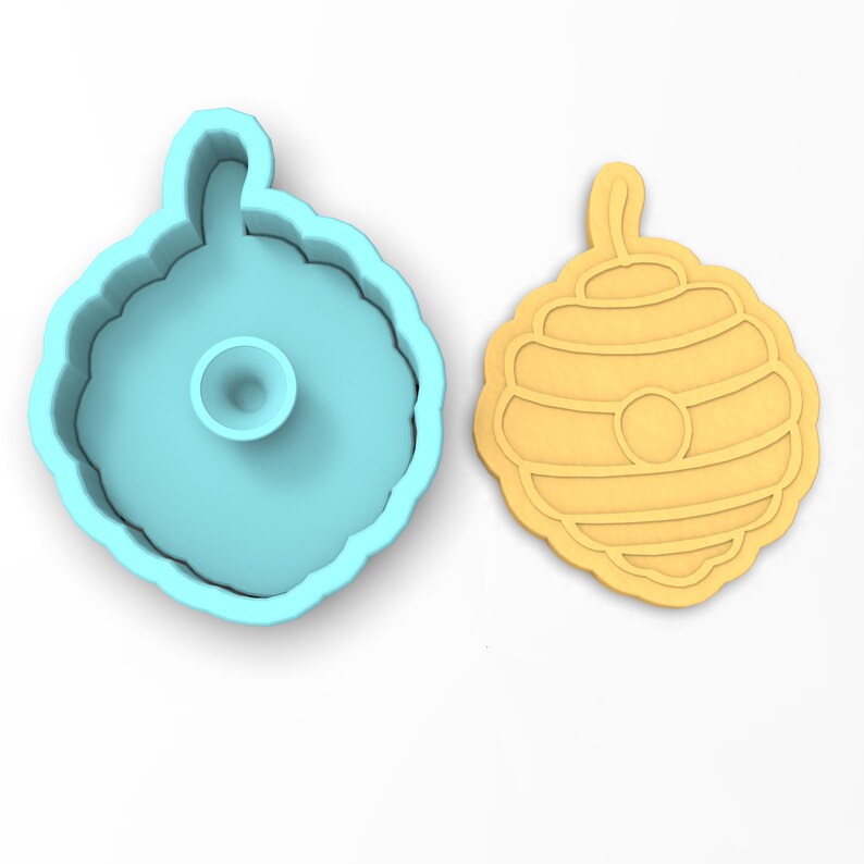 May include: A blue plastic cookie cutter shaped like a honeycomb and a yellow cookie cut out in the shape of a honeycomb.