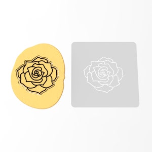 May include: A black and white outline of a rose flower on a yellow background. The rose is shown on a white square stencil.