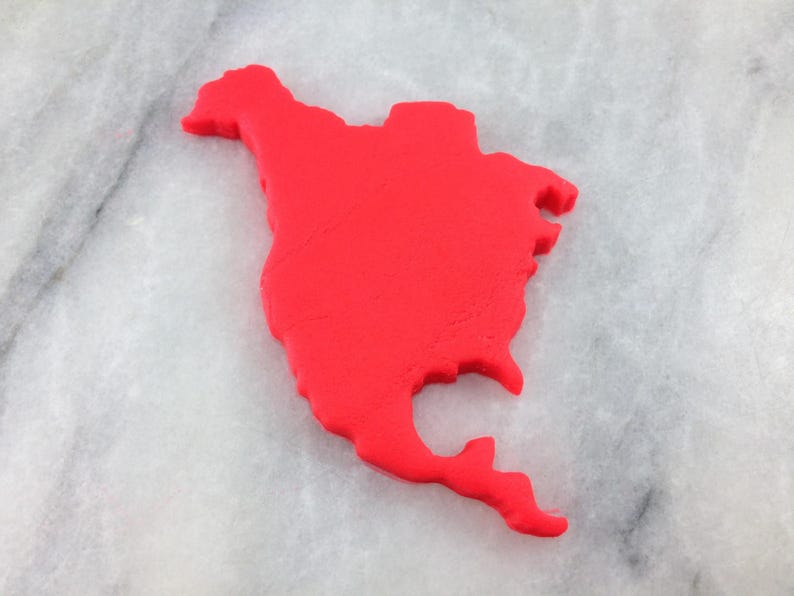 K&ouml;nnte beinhalten: Ein roter Playdough-Ausschnitt des nordamerikanischen Kontinents auf einer wei&szlig;en Marmorfl&auml;che.