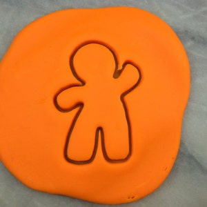 Może przedstawiać: Pomarańczowy fondant z wciśniętym w niego wykrawaczem do ciasteczek w kształcie piernikowego ludzika.
