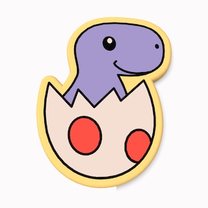 May include: A purple dinosaur hatching from a yellow egg with red spots. The dinosaur is smiling and has a small eye.
