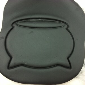 May include: Black fondant cookie cutter shaped like a cauldron with a rounded top and a wide base.
