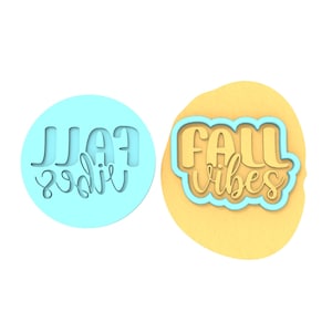 Op de afbeelding: Een lichtblauwe cirkelvormige koekjesvorm met de woorden "FALL vibes" in een scriptlettertype. Daarnaast een gele koek met de woorden "FALL vibes" in een scriptlettertype met een lichtblauwe omtrek.
