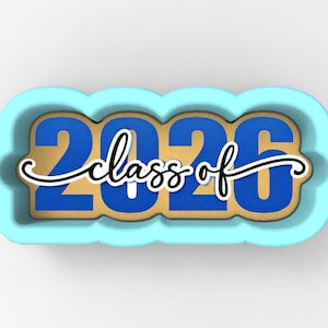 May include: A light blue cookie cutter with the text "2026 class of" in blue and white. The numbers "2026" are in a bold, sans-serif font. The words "class of" are in a cursive font.