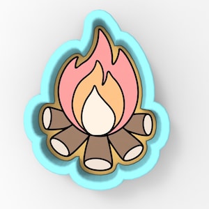 May include: A light blue cookie cutter in the shape of a campfire. The fire is depicted with pink, orange, and white flames, and the logs are brown with white tips. The cookie cutter is designed for baking.
