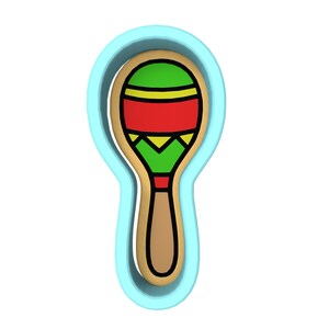 Puede incluir: Un cortador de galletas de plástico azul con forma de maraca. La maraca está decorada con rayas rojas, amarillas y verdes.