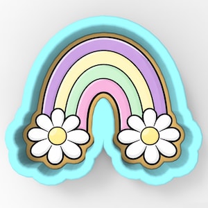 May include: A light blue cookie cutter shaped like a rainbow with daisies. The rainbow features stripes of purple, yellow, green, and pink. The daisies have white petals and yellow centres, with a brown outline.