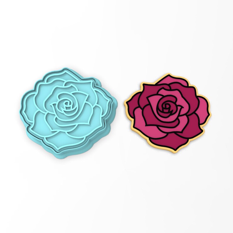 May include: A blue plastic cookie cutter shaped like a rose, next to a pink and red cookie in the shape of a rose.