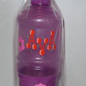 May include: A purple water bottle with a lid and a cup attached. The bottle is decorated with red cherries and the name "AVA" in orange letters. The cup has a pink flower design.