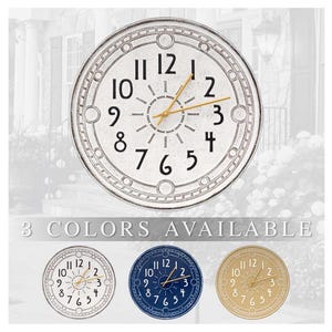 May include: Three round clocks with Roman numeral faces. The clocks are white, blue, and beige. The clock hands are gold. The text "3 COLORS AVAILABLE" is below the clocks.