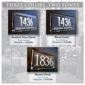 May include: Three house number signs with different finishes: brushed silver, black, and bronze. Each sign features the number "1436" or "1836" with the street name "SQUAW VALLEY DR." and the font options "TRAJAN or FUTURA".