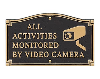 Peut inclure: Panneau en métal noir et or avec le texte "ALL ACTIVITIES MONITORED BY VIDEO CAMERA" et une silhouette dorée d'une caméra de sécurité.