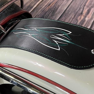 K&ouml;nnte beinhalten: Schwarzer Leder-Kotfl&uuml;gelspitzen mit einem gr&uuml;n-wei&szlig;en Pinselstrich-Design. Die Kotfl&uuml;gelspitze hat einen gr&uuml;nen gen&auml;hten Rand und eine silberne Schraube.