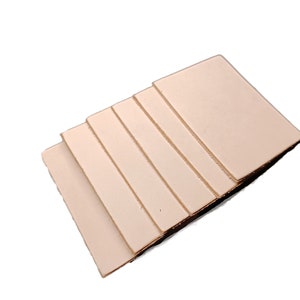 May include: A stack of six light beige leather squares, each with a smooth, slightly textured surface.