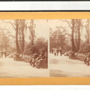 May include: Sepia-toned stereoscopic photograph of a park scene with people. The image is labeled "European & American Views." People are seated on benches and walking along a path lined with trees.