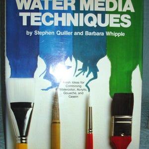 May include: A book titled "WATER MEDIA TECHNIQUES" by Stephen Quiller and Barbara Whipple. The cover features a blue, dark blue, and green background with paintbrushes. The text reads "Fresh Ideas for Combining Watercolor, Acrylic, Gouache, and Casein."