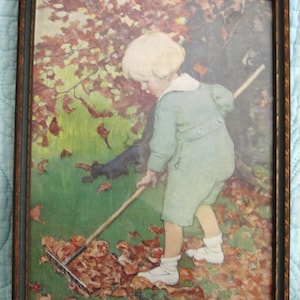 May include: A framed print depicts a child raking leaves in a yard. The child, dressed in a green outfit, is focused on the task. The artwork features a brown frame and a colorful autumn scene with a dog.