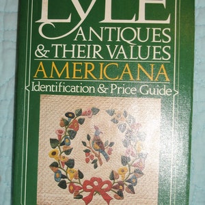 May include: A green book titled "The Lyle Antiques & Their Values Americana." The cover features a floral wreath with a bird and a red bow. The book is an identification and price guide with over 2000 items.