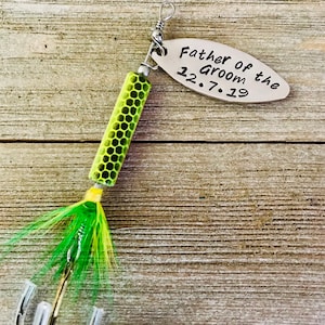 Pu&ograve; includere: Un'esca da pesca verde e gialla con un'etichetta argentata che recita "Father of the Groom 12.7.19".