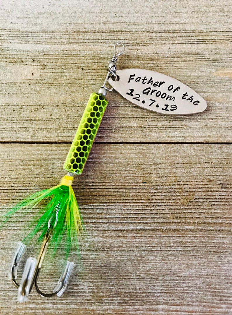 Pu&ograve; includere: Un'esca da pesca verde e gialla con un'etichetta argentata che recita "Father of the Groom 12.7.19".