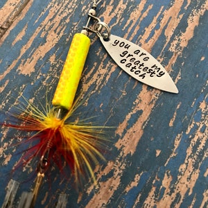 May include: A yellow and red fishing lure with a silver charm that says "You are my greatest catch".