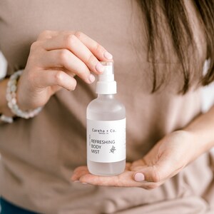 May include: A clear glass bottle with a white label that reads "Careha + Co. Refreshing Body Mist".